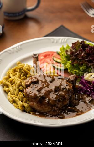 steak d'oeil côtelé avec salade de spaetzle sur tapis en cuir et table en bois sur fond flou Banque D'Images