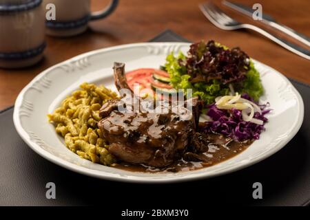 steak d'oeil côtelé avec salade de spaetzle sur tapis en cuir et table en bois sur fond flou Banque D'Images