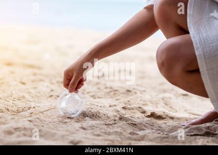 Un nettoyage des mains et ramasser un verre plastique poubelle sur la plage Banque D'Images