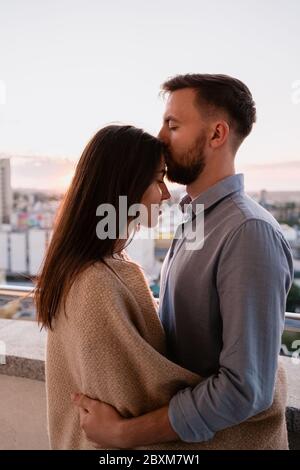 Gros plan portrait, homme et femme souriant les uns aux autres au coucher du soleil avec la ville en arrière-plan. Couple romantique moments intimes Banque D'Images