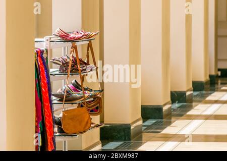 Étagère avec chaussures, sacs et foulards artisanaux indiens en solde dans une galerie de colonnes Banque D'Images