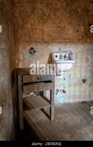 Intérieur d'une cellule dans une prison abandonnée avec de vieux toilettes, lavabo et bureau. Banque D'Images