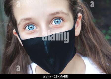 Préadolescence caucasienne fille dans un tissu masque de poussière à l'extérieur. Gros plan portrait. Les gens, les soins de santé, le coronavirus, le concept de retour à l'école Banque D'Images