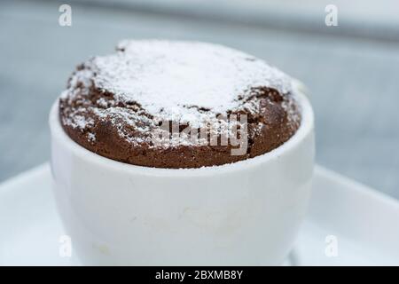 Un dessert français traditionnel - « soufflé », gâteau au chocolat chaud, servi dans une tasse, recouvert de sucre en poudre. Banque D'Images