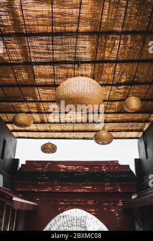 Lampe en osier orange faite à la main dans un intérieur sombre avec des murs noirs. Concept écologique et naturel dans le design intérieur. Toit de café moderne. Style simple et contemporain. Banque D'Images