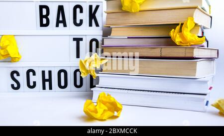 Visionneuse avec TEXTE ET livres DE RETOUR À L'ÉCOLE sur fond blanc avec papier jaune froissé Banque D'Images