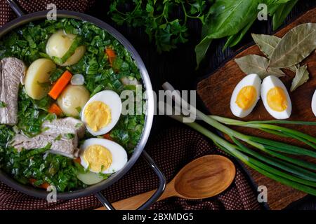 Feuilles d'été, borscht d'oseille ou soupe d'oseille fraîche, oignon vert avec côtes de porc, jeunes pommes de terre, carottes et œufs durs, servi dans une casserole sur un bon Banque D'Images