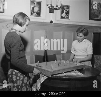 Dans les années 1950. Deux filles jouent au jeu de hockey sur glace Puck. Fabriqué par la société suédoise Aristopel. À ce moment breveté et seul sur le marché pour vendre le jeu. Les joueurs manœuvrent les figures sur la planche en les déplaçant et en les tordant autour et comme les vrais hockeyplatjoueurs déplacent le palet autour pour essayer de marquer un but. années 1950 Banque D'Images