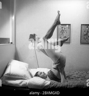 Exercice du matin dans les années 1940. Une jeune femme est allongée dans le lit et tient ses jambes tout en se déplaçant autour pour obtenir la forme pour la journée. Suède 1946. Kristoffersson réf. Y21-6 Banque D'Images