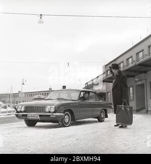 Couple dans les années 1960. Une femme a conduit son mari à l'aéroport et l'a déferé de sa voiture, un modèle spécial 1961 de Buick. C'est une journée d'hiver à l'aéroport de Bromma à Stockholm. Suède 1961. Kristoffersson réf. CS5-8 Banque D'Images