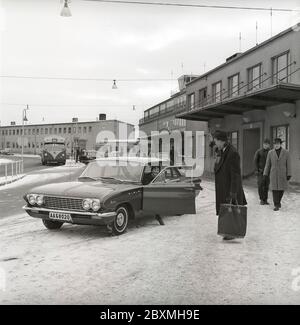 Couple dans les années 1960. Une femme a conduit son mari à l'aéroport et l'a déferé de sa voiture, un modèle spécial 1961 de Buick. C'est une journée d'hiver à l'aéroport de Bromma à Stockholm. Suède 1961. Kristoffersson réf. CS5-10 Banque D'Images