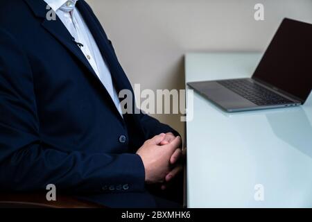 Un homme de direction élégant en costume bleu foncé s'entretient dans son bureau et est attaché un micro sur le dessus de la combinaison. Banque D'Images