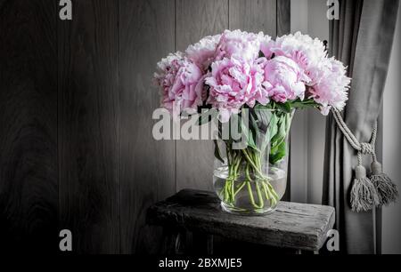 Pivoines roses dans un vase sur une table rustique en bois. Décoration romantique. Banque D'Images