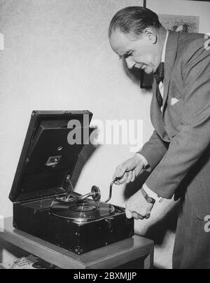 Hugo Lindh. 1899-1979. Compositeur suédois à domicile exploitant son lecteur de gramophone portable. Il est actionné en l'enroulant vers le haut à l'aide d'un levier. L'enregistrement est alors lu. Lorsque vous entendez que l'enregistrement commence à ralentir, vous savez que vous devez me remonter. Les enregistrements ont été faits de matériaux fragiles et la vitesse de l'enregistrement à sonner comme il devrait être de 78 tours par minute. Suède années 1940. Banque D'Images