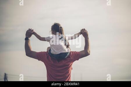 Père et enfant heureux de famille sur la prairie avec un cerf-volant en été sur la nature. Vue arrière du père portant sa petite fille sur les épaules. Père Banque D'Images