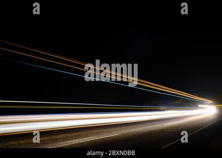 Des pistes lumineuses de voitures sur l'autoroute en pleine exposition nocturne. Banque D'Images
