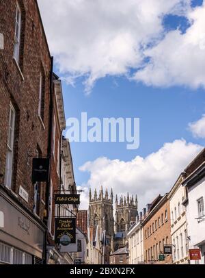 Dans Low Petergate York avec ses boutiques et les tours de la cathédrale de York dans l'arrière-plan Banque D'Images