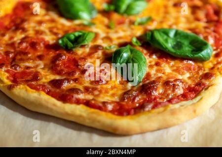 Gros plan vue panoramique peu profonde de la savoureuse pizza italienne cuite maison à la Margarita sur du papier de cuisson juste préparé au four. Fromage mozzarella fondu Banque D'Images