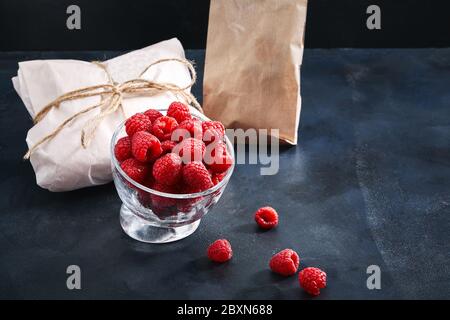 Framboises fraîches dans une assiette sur fond bleu. Concept de livraison alimentaire, emballage écologique. Espace de copie, gros plan Banque D'Images