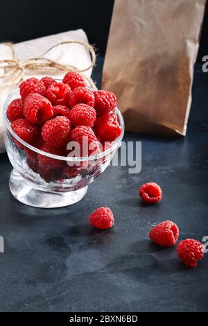 Framboises fraîches dans une assiette sur fond bleu. Concept de livraison alimentaire, emballage écologique. Espace de copie, gros plan Banque D'Images