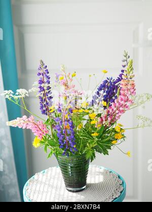 Vase en verre avec bouquet de belles fleurs sauvages sur fond blanc. Lupins dans un vase. Banque D'Images