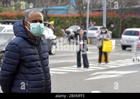 Les personnes portant un masque facial qui garde la distance de sécurité à l'extérieur d'un supermarché pendant l'urgence Covid-19, à Milan, en Italie. Banque D'Images