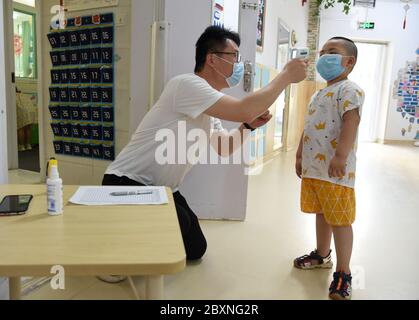 (200608) -- JINAN, 8 juin 2020 (Xinhua) -- UN enfant obtient sa température mesurée avant d'entrer dans une salle de classe à un jardin d'enfants à Jinan, dans la province de Shandong, en Chine orientale, 8 juin 2020. Les jardins d'enfants de Jinan ont rouvert lundi dans le cadre des mesures de prévention et de contrôle de la COVID-19. (Xinhua/Wang Kai) Banque D'Images