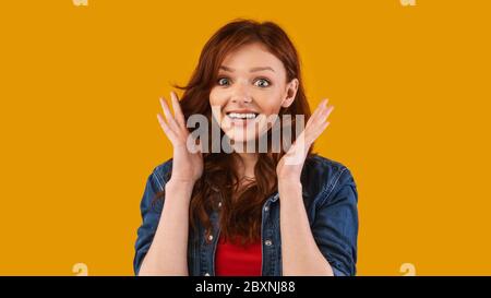 Une jeune fille surprise regarde la caméra poser sur un fond jaune Banque D'Images