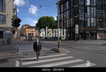 Homme solitaire portant un masque santé marche sur la ville de quarantaine, en raison de la crise saine Covid-19, à Milan, en Italie. Avril 2020. Banque D'Images