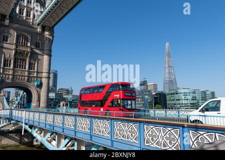 Londres bus rouge à impériale traversant Tower Bridge dans une belle journée ensoleillée avec un ciel bleu sans nuages. Banque D'Images