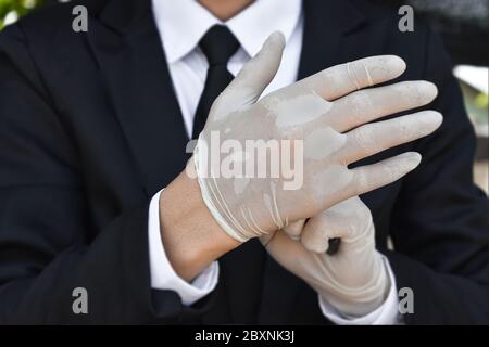 Gros plan sur un homme d'affaires portant des gants en latex blanc. Concept de protection des soins de santé contre le virus corona ou covid-19 au travail. Banque D'Images