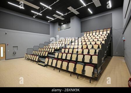 Sièges amovibles dans une salle d'école récemment construite dans le sud de Londres, Royaume-Uni. Montre que le système est complètement étendu et que 9 rangées de sièges sont rangées. Banque D'Images