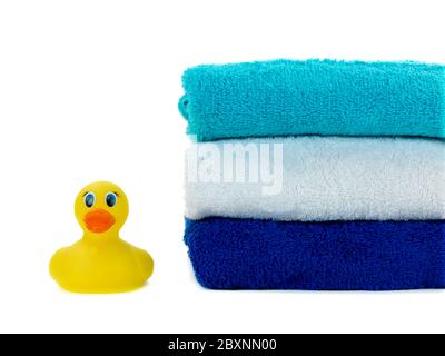 Une pile de serviettes de bain et un canard en caoutchouc isolé sur fond blanc Banque D'Images