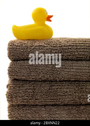 Une pile de serviettes de bain et un canard en caoutchouc isolé sur fond blanc Banque D'Images