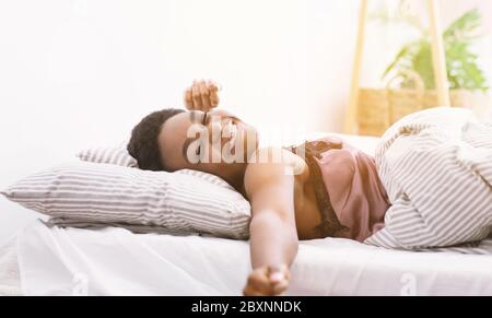 Bonne journée de début de journée. Une fille afro-américaine s'est réveillée et s'est mise au lit à la lumière du matin Banque D'Images