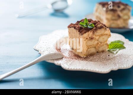 Tiramisu italien dessert sur assiette de porcelaine fond bleu Banque D'Images