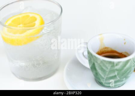 Verre d'eau pétillante avec citron et tasse de café. Eau minérale glacée avec citron et une tasse de café sur la table blanche. Banque D'Images