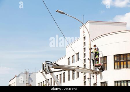 Belgrade, Serbie - 24 avril 2020 : ouvrier de construction dans un panier de grue, un préparateur de cerises, en installant un support métallique sur un poteau de feu de rue Banque D'Images