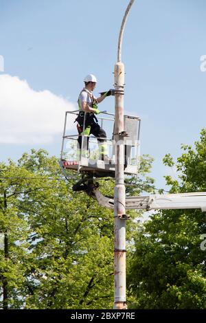 Belgrade, Serbie - 24 avril 2020 : ouvrier de construction dans un panier de grue, un préparateur de cerises, en installant un support métallique sur un poteau de feu de rue Banque D'Images