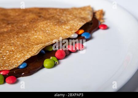 crêpe au chocolat avec lentilles au chocolat et caramel coloré. Image isolée Banque D'Images