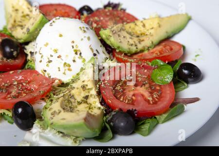 Salade de mozzarella avec tomates avocat et olives noires. Image isolée. Mise au point sélective. Banque D'Images