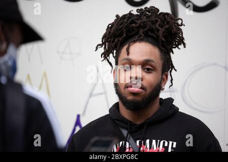Un jeune homme, avec une barbe taillée et des dreadlocks, se tient devant un mur de graffiti pendant la Black Lives Matter protestation britannique. Londres, Angleterre Royaume-Uni Banque D'Images