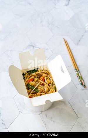 Retirez les nouilles thaï asiatiques avec crevettes et arachides écrasées dans un contenant en plastique. À emporter. Prêt à manger. Banque D'Images