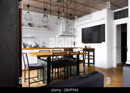 Moderne scandinave un décor intérieur de cuisine avec une grande table en bois et des chaises contre le sol en bois clair, des murs blancs lumineux et des meubles Banque D'Images