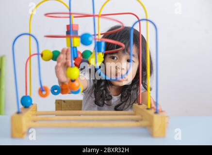 Asiatique autiste fille se concentrant jouant avec des blocs. La fille ne répond pas au monde autour de nous. Immergé dans la pensée. Mise au point sélective Banque D'Images