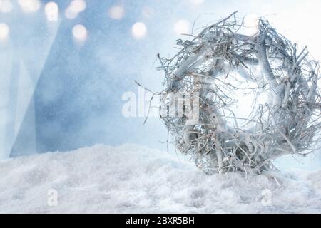 Couronne de noël blanche et guirlande lumineuse dans la neige avec bokeh argent brillant pour une décoration d'hiver Banque D'Images