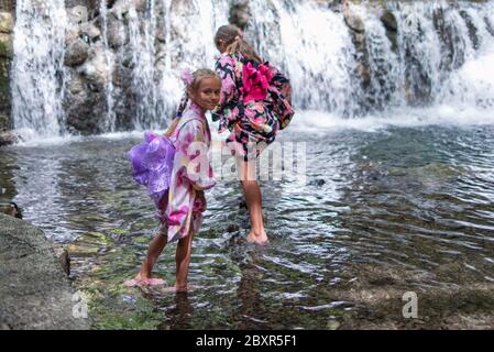 Filles européennes en vêtements kimano.deux petites filles vêtues de vêtements kimano se tiennent près d'une petite cascade dans un restaurant aquatique. Banque D'Images