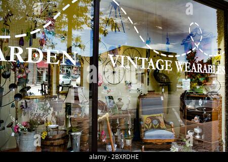 Vue à travers la fenêtre de la façade du magasin avec des panneaux sur le verre de divers antiquités et des objets d'époque dans le centre-ville de St. Cloud, MN, États-Unis Banque D'Images