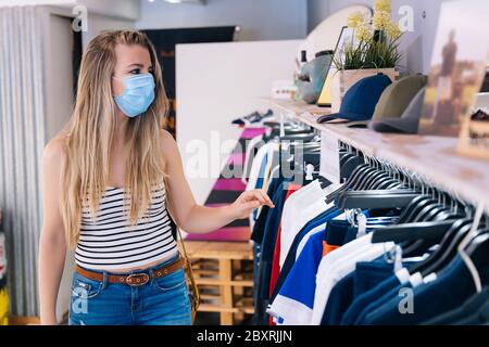 Femme en masque magasiner dans un magasin de vêtements dans la pandémie de coronavirus Banque D'Images