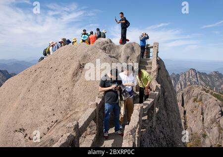 Huangshan Mountain dans la province d'Anhui, Chine. Marcheurs avec téléphones cellulaires au sommet de Lotus Peak sur Huangshan. Banque D'Images